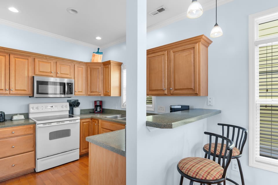 Your fully equipped kitchen features warm wood cabinets, and a breakfast bar perfect for morning coffee and casual meals.