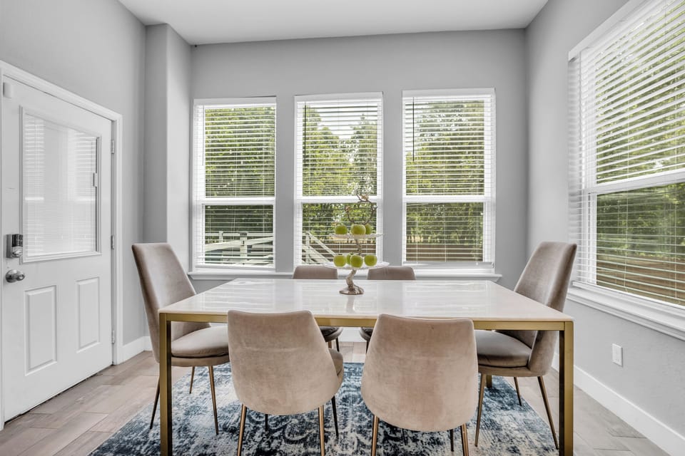 Dining room – bright table seating beside large backyard-facing windows.