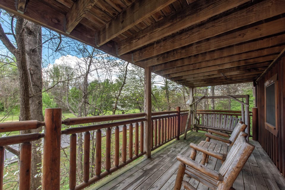 Unwind on your private covered deck with handcrafted log furniture while soaking in peaceful forest views through towering trees.