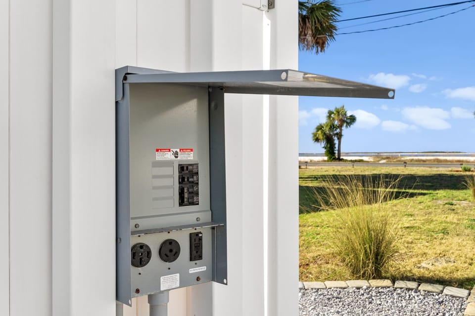 Electrical panel with coastal marsh and palm trees beyond property grounds.