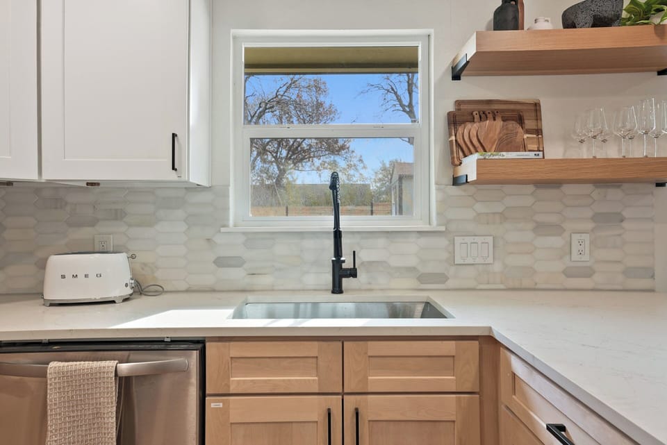 Kitchen sink, Smeg Toaster, cutting boards, wine glasses, cleaning supplies under the sink. 