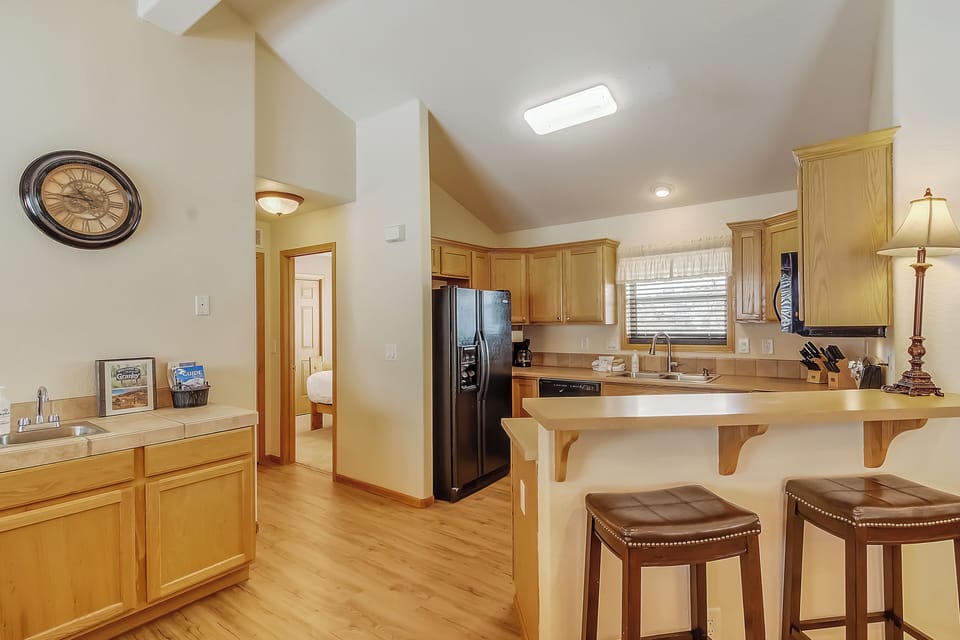 Your fully equipped kitchen welcomes you with warm wood cabinetry, granite countertops, and a cozy breakfast bar for morning coffee.