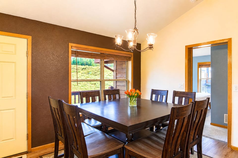 Your dining space features a handsome table for eight, warm wood tones, and a thoughtful accent wall—perfect for enjoying meals together while gazing out at the hillside views.