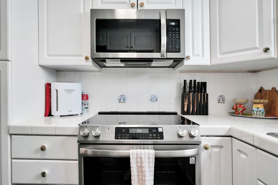 Your fully equipped kitchen features modern stainless steel appliances, pristine white cabinets, and everything you need to create memorable meals.