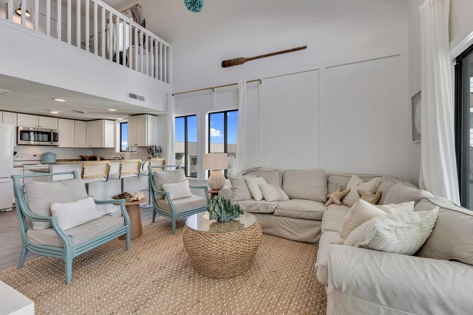 Relax in your spacious living area with plush seating and soaring ceilings that create an airy, coastal-chic atmosphere perfect for unwinding.