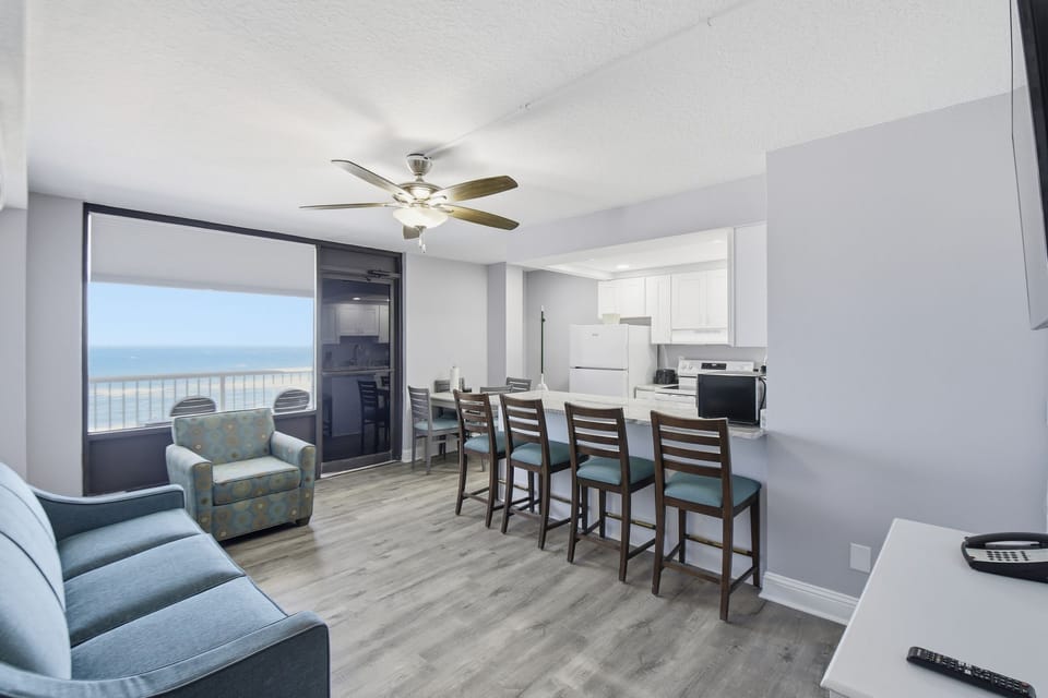 Experience coastal elegance in the spacious Caribbean Room, where natural light floods the modern living area, highlighting the chic decor and inviting views of the Atlantic.