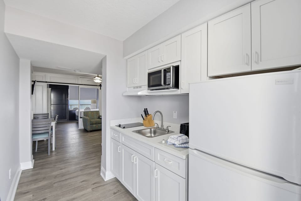 This modern kitchen is designed with white cabinetry and stainless steel appliances, including a stovetop, making meal preparation both efficient and enjoyable.