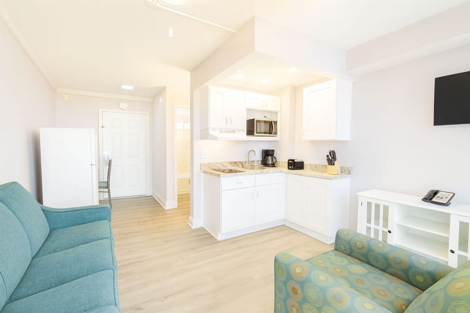 A welcoming living space showcases a comfortable sofa and a functional kitchenette, ideal for family gatherings or a romantic getaway.