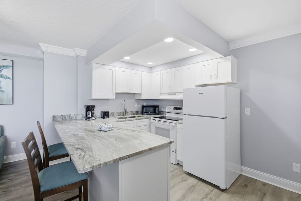 The kitchen reveals an extended breakfast bar, perfect for casual dining or entertaining, seamlessly connecting the cooking and living spaces.