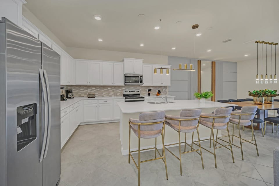Sleek kitchen w/ stainless appliances, white cabinetry & a large island to gather around.

