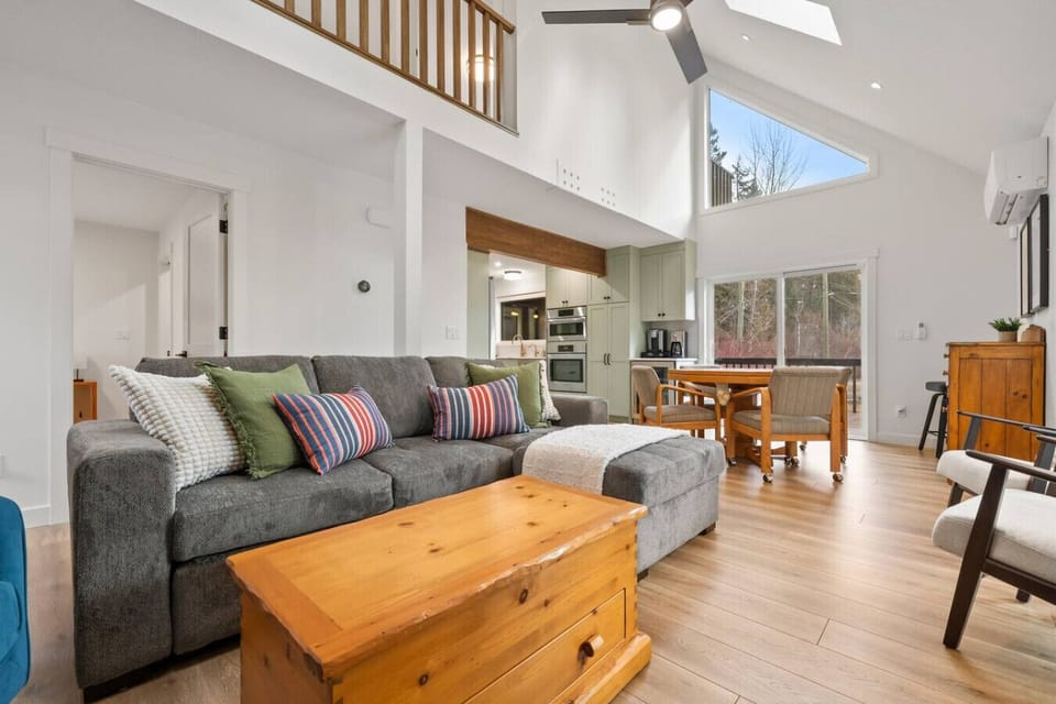 Main-floor living room with a 55` TV (cable & Disney+), board games, game table, and cozy seating including a double-size pullout sleeper sofa. All linens provided.