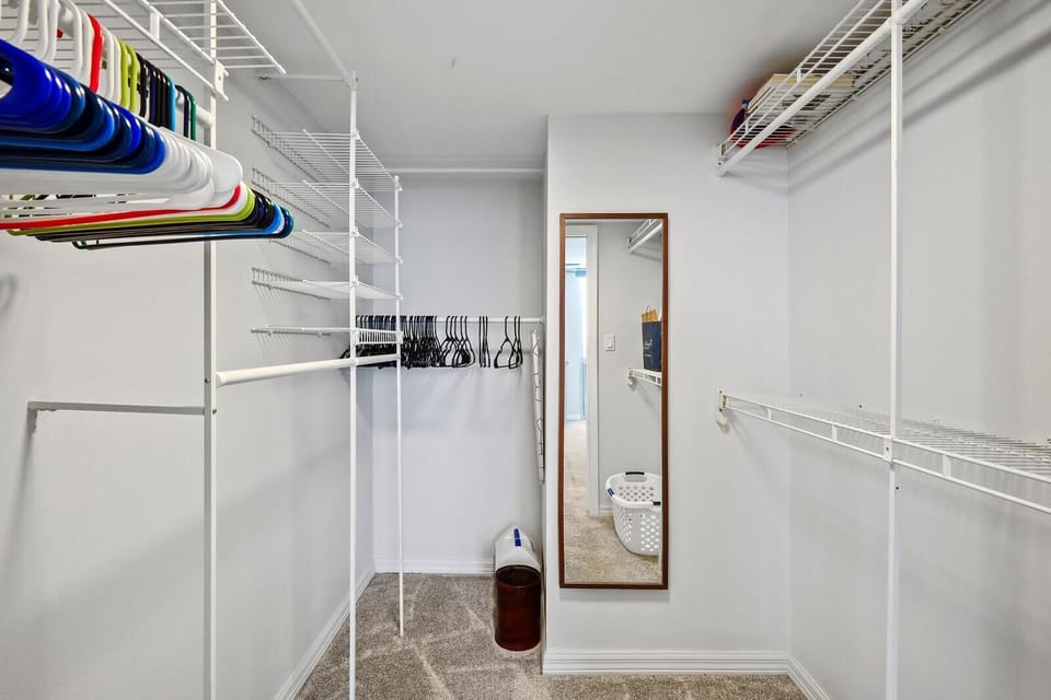 Spacious walk-in closet with organized shelving and full-length mirror
