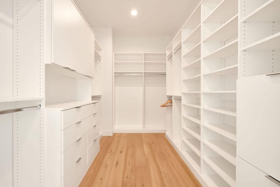 Primary bedroom featuring a King bed, plush furnishings, dresser, large walk-in closet, and an en-suite bathroom.