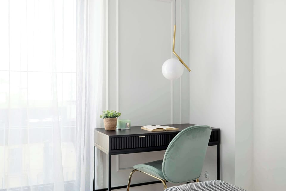 Bedroom corner with a desk, chair, and natural daylight.