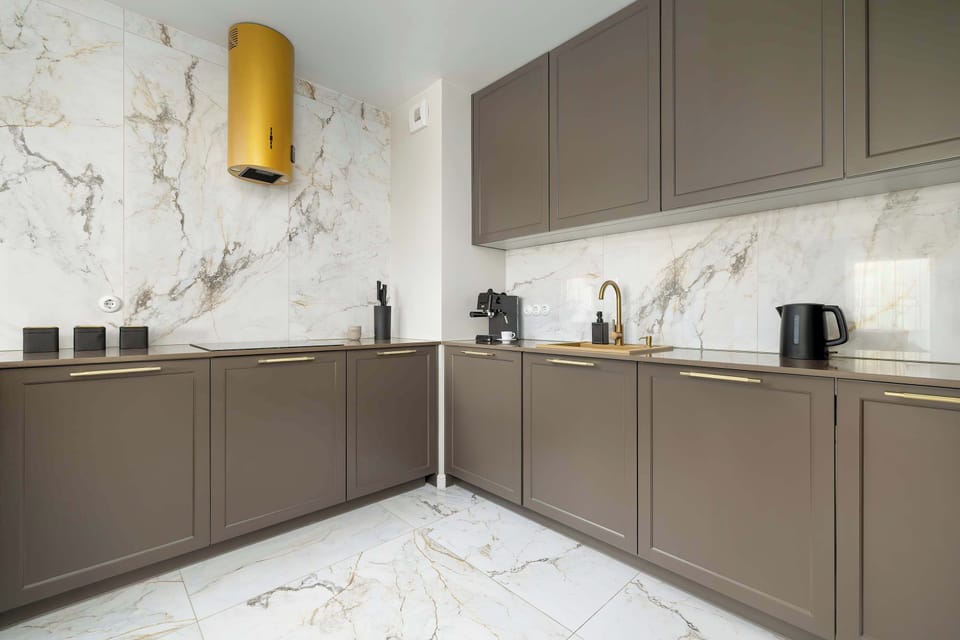 Modern kitchen with elegant cabinetry, marble-style floor, and gold accents.