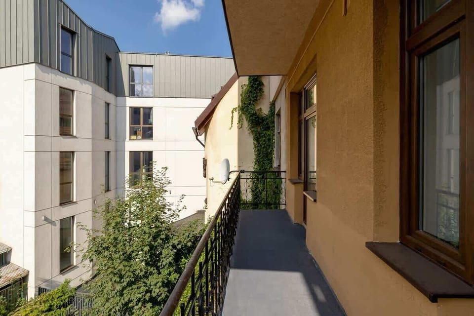 A view of the building’s balcony, overlooking greenery and modern neighboring structures.
