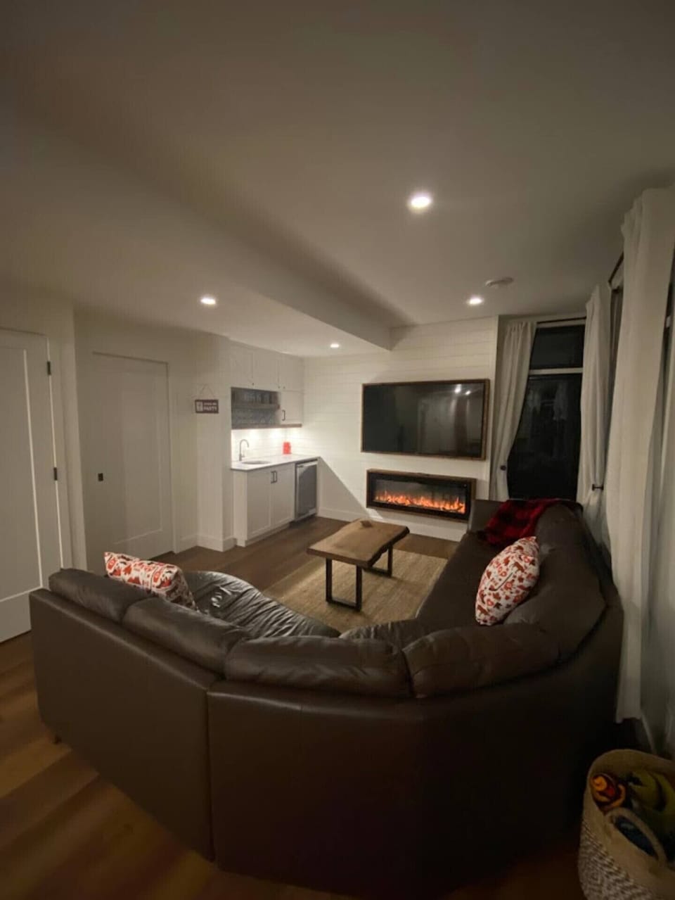 Lower level entertainment area showing fireplace, smart TV, kitchenette and group seating