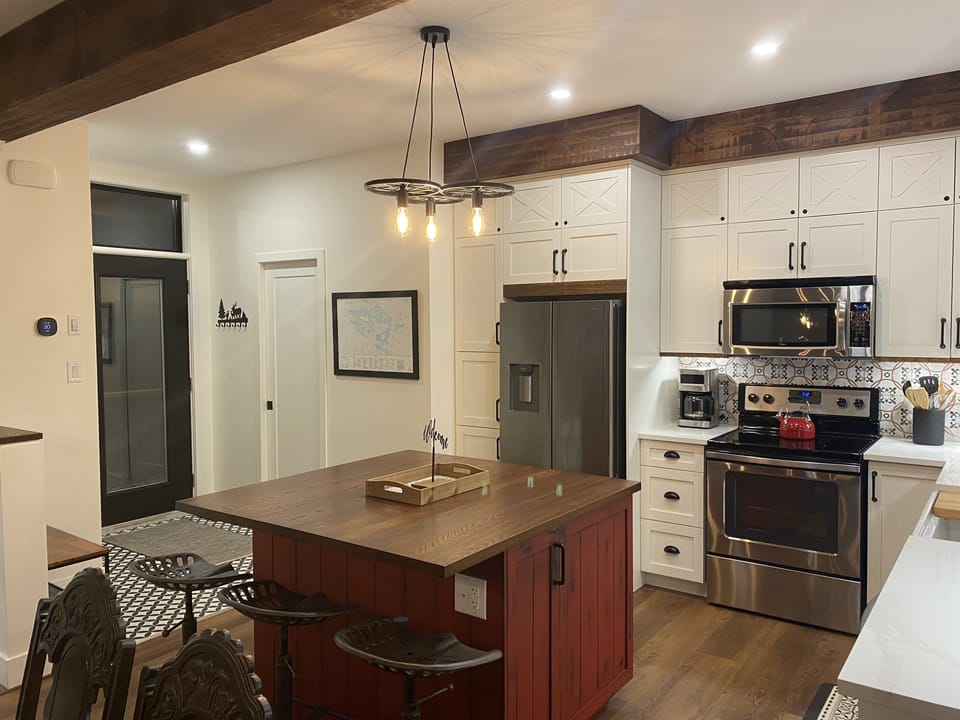 Well-equipped kitchen with island, custom cabinetry and cottage main entrance door  nearby