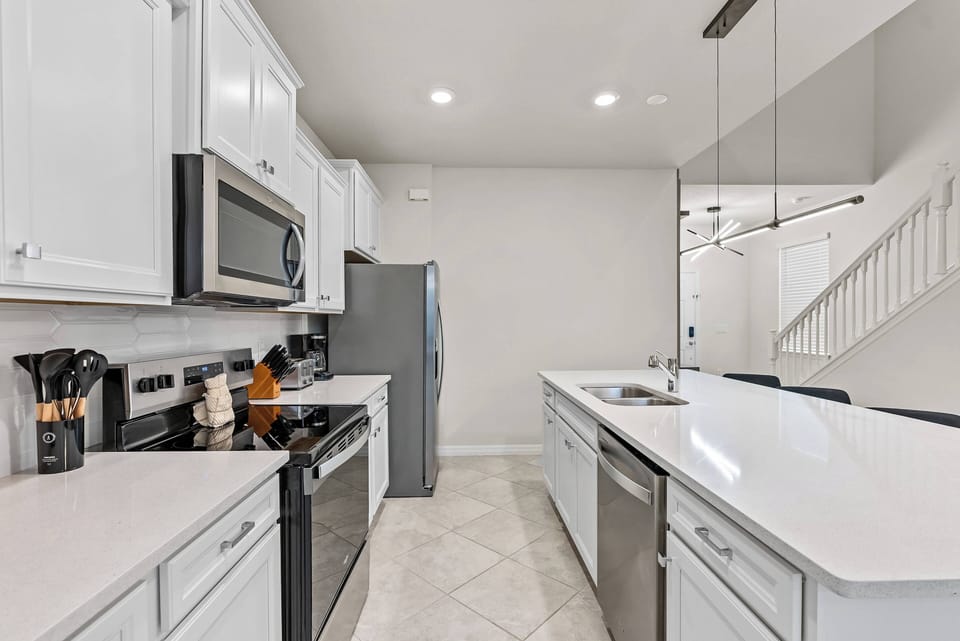 This bright kitchen features sleek white cabinetry and a spacious island perfect for culinary creativity. With stainless steel appliances and ample counter space, it invites you to relax and prepare delightful meals.