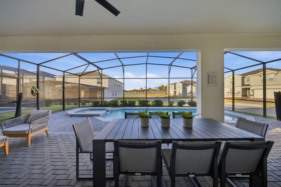 Step outside to a spacious covered patio featuring a large dining table perfect for your next meal. Enjoy the refreshing pool view and relax in comfort with seating that invites you to unwind under the gentle breeze.