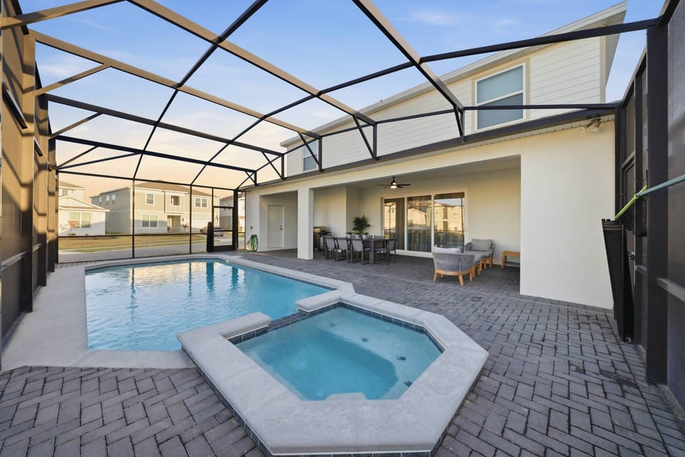Discover your outdoor oasis with a sparkling pool and a soothing hot tub beneath a spacious screened enclosure. The stylish patio furniture invites relaxation, making it perfect for sun-filled days and cozy evening gatherings.