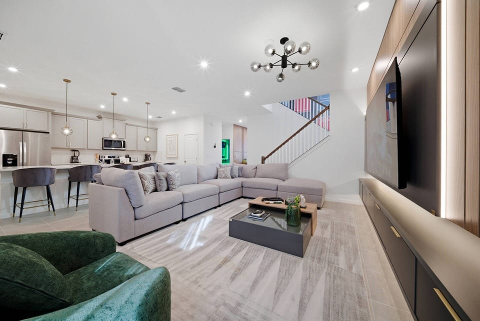 Welcome to a bright living room with a spacious gray sectional and stylish accent chairs, where modern decor and warm lighting create a cozy atmosphere ideal for relaxing after your day of adventure.
