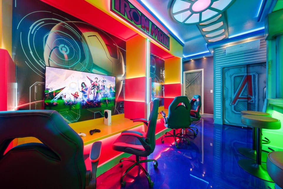 Step into this vibrant gaming room, where neon lights glow on the sleek blue floor and colorful graphics create an energetic vibe. With comfy gaming chairs and a large screen, this space is perfect for fun and relaxation.