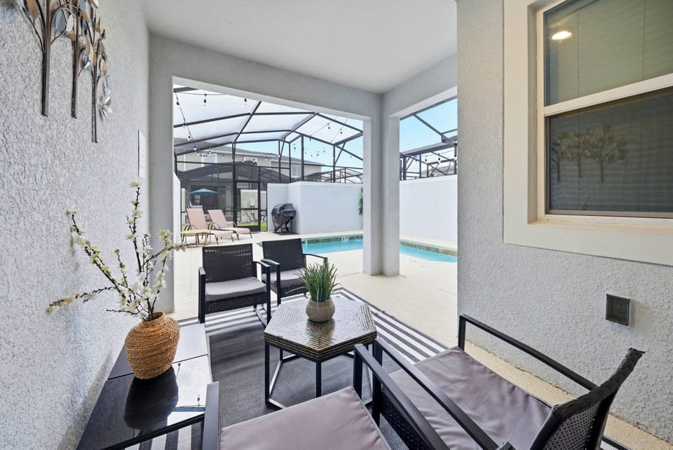 Experience your private oasis in this chic outdoor seating area with sleek black furniture and an elegant vase. Take in the stunning pool view, expertly framed by a protective screen for comfort and relaxation in any weather.