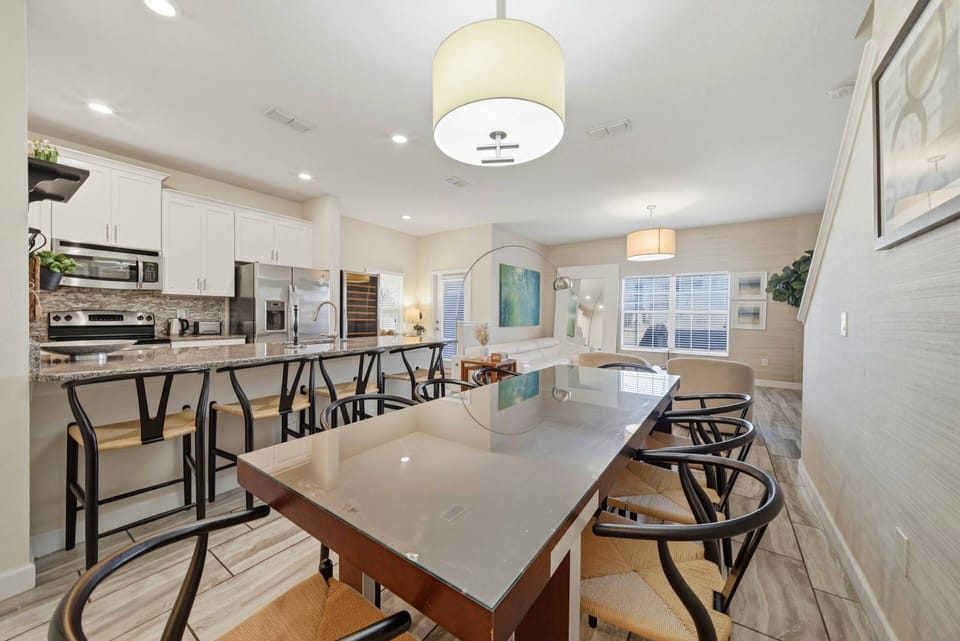Step into a well-lit kitchen featuring sleek, modern cabinetry and a spacious island perfect for casual dining. The stylish bar stools invite you to gather while the easy flow between spaces enhances your culinary experience.