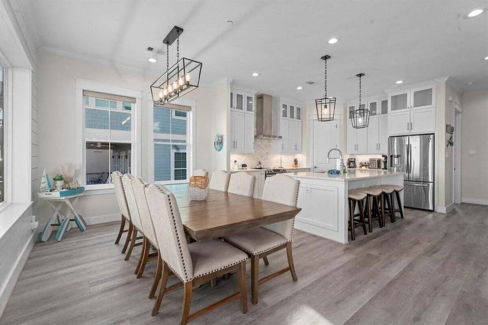 Bright dining area with modern lighting and seating for large groups in this luxury Galveston vacation rental.