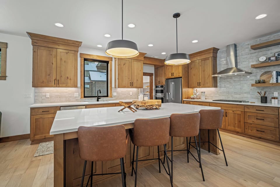 Your gourmet kitchen awaits with warm wood cabinetry, marble countertops, and modern pendant lighting—perfect for cooking memorable meals together.