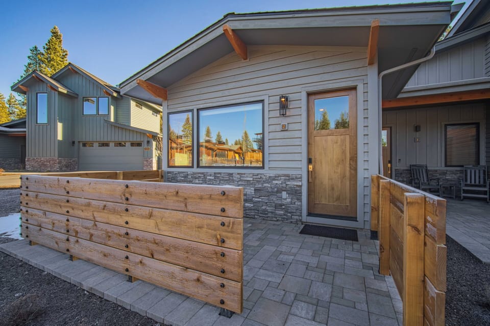 Modern mountain retreat with stone accents and wooden details creates a welcoming arrival experience in this scenic neighborhood setting.