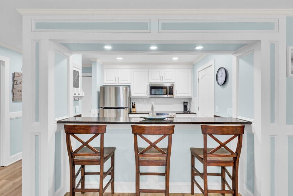 Your modern kitchen features sleek white cabinets, stainless appliances, and a breakfast bar perfect for morning coffee.