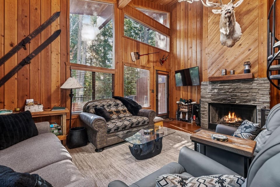 Cozy up by the crackling fireplace in this rustic living room, where warm wood walls and comfortable seating create your perfect mountain retreat.