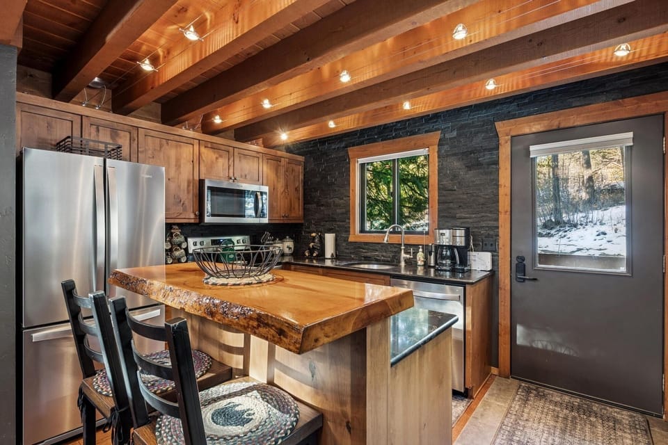 Your rustic-modern kitchen blends warm wood beams with sleek stainless appliances, perfect for cooking mountain meals.