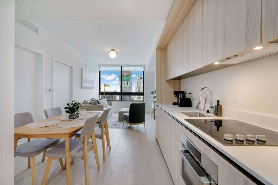 Cook with a view. Our sleek, modern kitchen is fully equipped with integrated appliances, light wood cabinetry, and all the essentials needed to prepare a gourmet meal at home.
