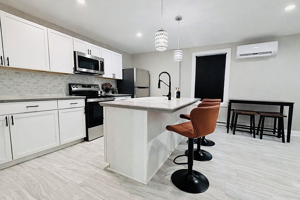Fully updated kitchen featuring white cabinetry, stainless appliances, and a large island with bar seating—ideal for meals, snacks, and gathering with family or friends.