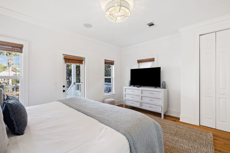 Your peaceful bedroom features a plush king bed, stylish TV entertainment, and serene natural light streaming through multiple windows.