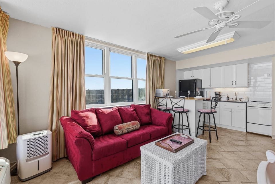 This inviting beach stay condo features a comfortable living area, large windows with natural light, and a convenient kitchenette with breakfast bar. The perfect vacation rental retreat just steps from the sand and surf.
