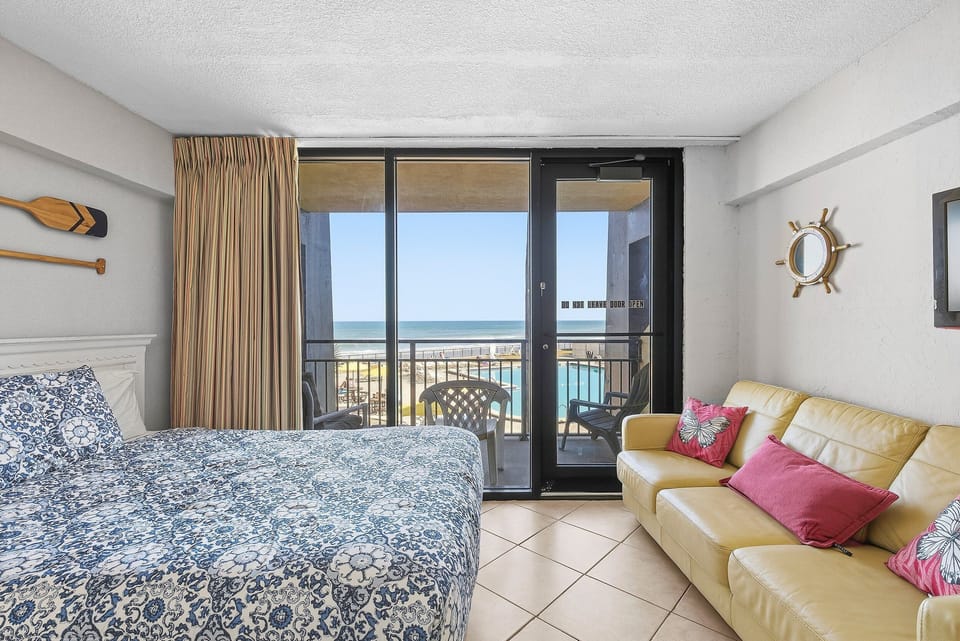 Wake up to ocean views at this inviting beach stay featuring a cozy bed, comfortable seating, and a private balcony overlooking the pool and shoreline. This coastal vacation rental blends comfort, relaxation, and seaside charm.