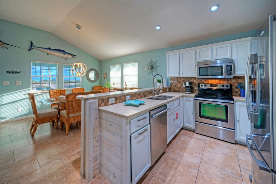Kitchen area with white cabinetry, stainless steel appliances, and a breakfast bar.