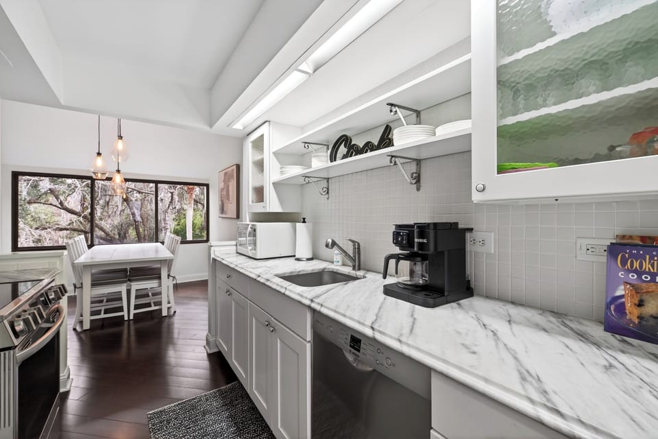 Well-appointed kitchen featuring ample prep space, a modern coffee station, and views of the dining area.