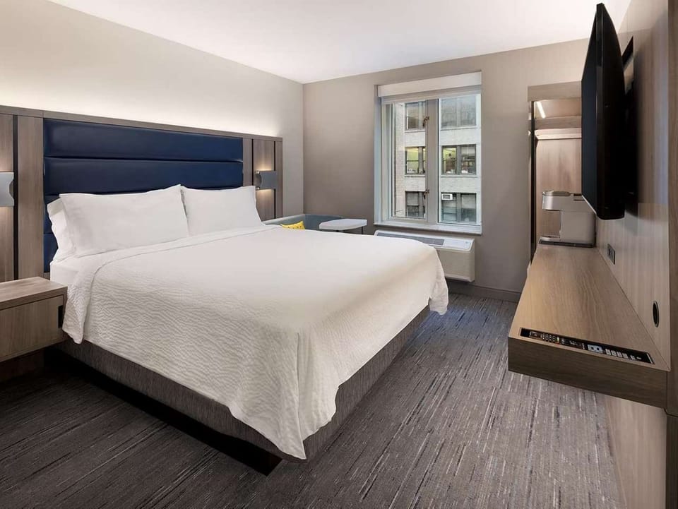 Spacious king bed with soft linens and wall-mounted TV
