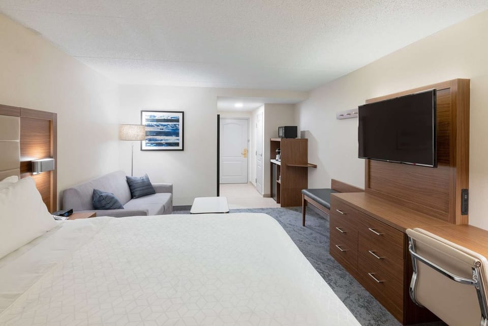 King bed room with sofa, desk, TV, and soft lighting