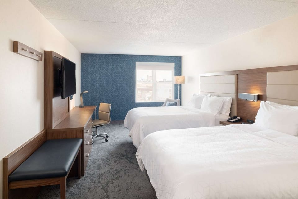 Room with two queen beds, work desk, TV, and large window