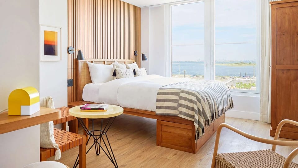 King bed with wood slat headboard, round table, and bay view