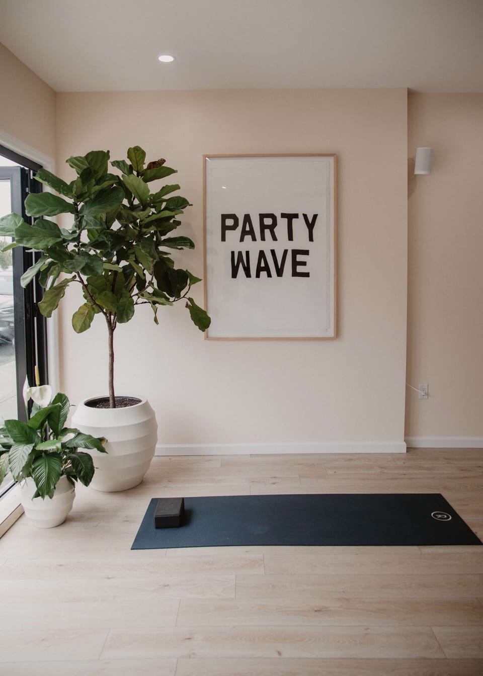Minimal wall art reading “Party Wave” beside indoor greenery