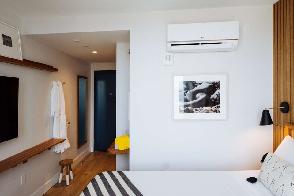 Room entry with wall-mounted screen, robes, shelf, and wood floors
