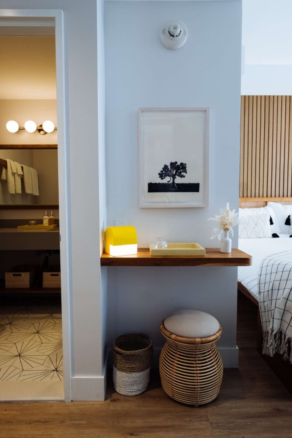 Vanity nook with framed art, woven stool, and bathroom entry