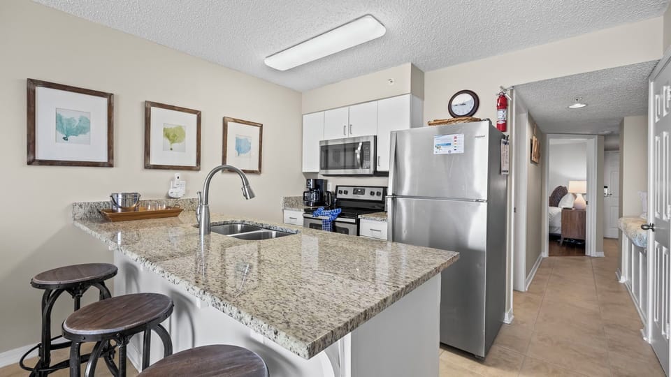 Royal Palms 1006 - Kitchen featuring counterspace with three stools, perfect for meal prep and casual dining.